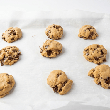 Tray of fresh-baked chocolate chip cookies cooling on parchment paper