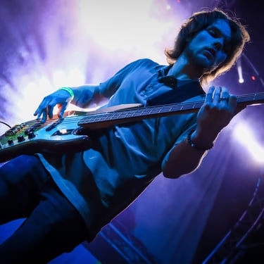 Thomas jouant de la basse avec energie lors du festival du petit wood de sémeries sous le feu des projecteurs 