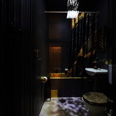 Black and gold styled bathroom with golden bathtub.