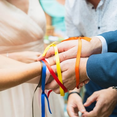 Rituel des rubans colorés lors d’un mariage, illustrant la coordination du jour J par Clair Agence