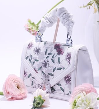 White bag with a floral pattern surrounded by flowers
