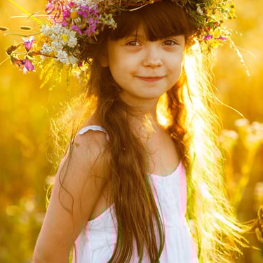 a young girl wearing a flower crown in a field