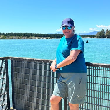 a woman standing on a bridge over looking at the water