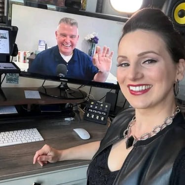 A woman smiling during a video call with a male colleague on a professional home office desk setup.