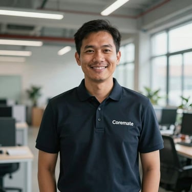 A Southeast Asian technical director in a professional dark polo shirt, standing in a brightly lit industrial office space. Confident and welcoming expression, representing the Coremate brand.