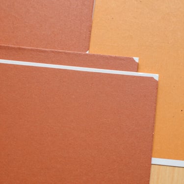 Close-up of thick, textured terracotta and warm ochre paint swatches layered artistically on a canvas, bright daylight, 35mm