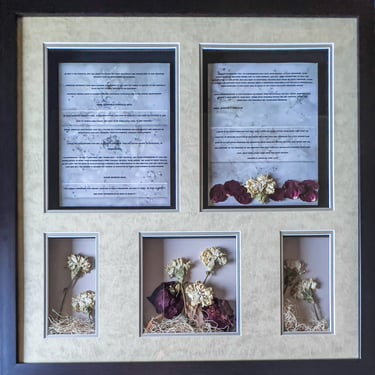 Framed wedding shadow box featuring marriage vows, preserved white carnations, and dried rose petals.