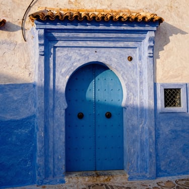 Historic architectural detail of an ancient blue doorway in Chefchaouen, warm sunlight