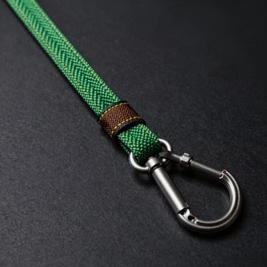 A heavy-duty climbing rope dog leash with a secure locking carabiner, close-up on the stitching, dark background