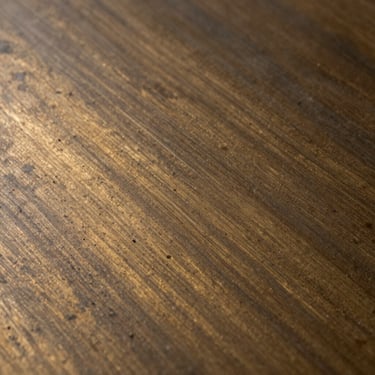 Macro shot of oil-rubbed bronze finish on a solid steel plate, showing warm golden-brown undertones and deep chocolate coloration.