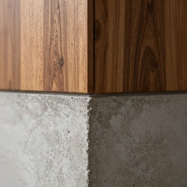 Close-up of a seamless corner transition where raw board-formed concrete meets a warm walnut wood panel, natural side lighting emphasizing texture