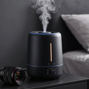 A sleek matte black portable mini humidifier emitting fine mist on a bedside table