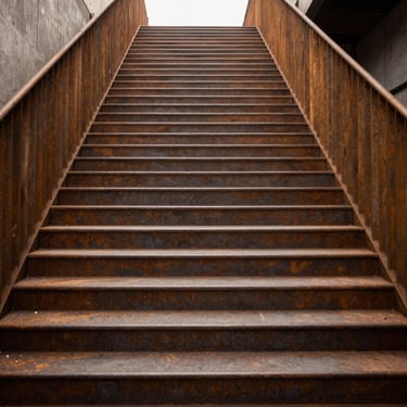 Escalier suspendu en acier brut et marches en chêne massif, lignes géométriques épurées, cadrage frontal strict.