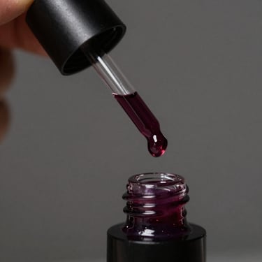 Sleek black glass applicator dripping with a rich, deep plum lip oil, chiaroscuro lighting