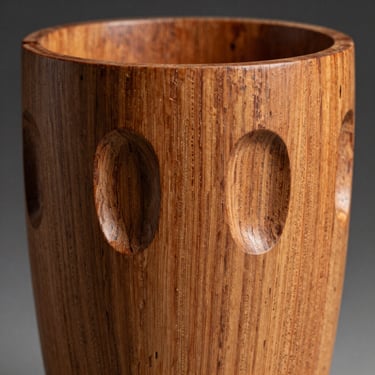 Close-up of a hand-carved decorative wooden vessel, showing intricate grain detailing and smooth, curved edges