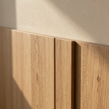 Close-up of high-quality architectural materials, light oak wood paneling meeting textured warm plaster, soft natural shadows.