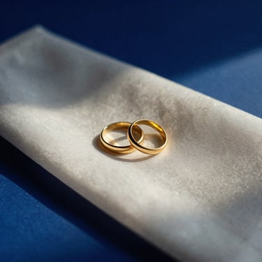 Elegant album artwork mockup for a contemporary wedding song, featuring two gold rings resting on white silk, soft golden-hour lighting, minimalist, 35mm