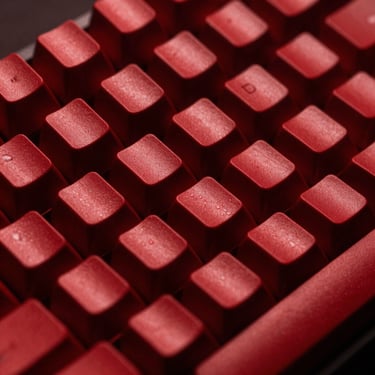 Macro close-up of a vintage mechanical keyboard with red keycaps, high contrast studio photography, dramatic red and black lighting, 50mm