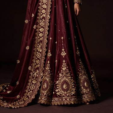 Opulent festive silk ensemble with heavy embroidery, dramatic low-key lighting highlighting the rich textures and deep maroon hues