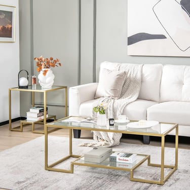 Modern glass coffee table and matching side table with gold metal frames in a contemporary living room.