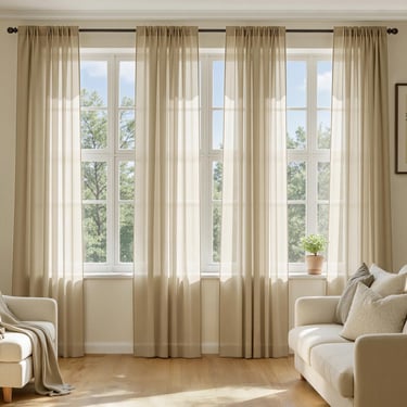 Elegant beige sheer curtains hanging over a large living room window with natural light.