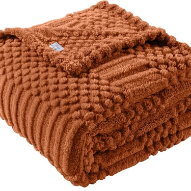 Folded burnt orange textured popcorn throw blanket with soft plush fabric for cozy home decor.