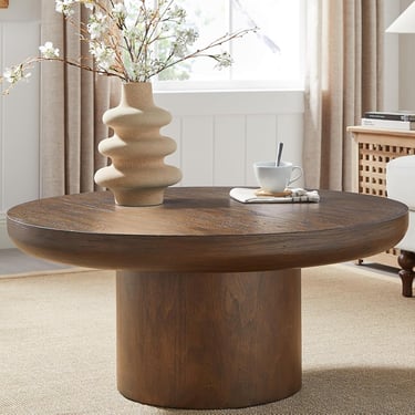 Round dark wood coffee table with a pedestal base and a decorative ceramic vase.