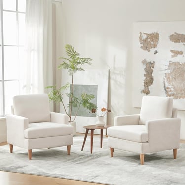 Two modern cream upholstered armchairs with wooden legs in a bright minimalist living room.