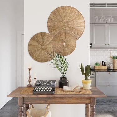 Vintage wooden desk with a retro typewriter and seagrass wall art in a modern grey kitchen interior.