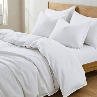 Crisp white cotton duvet cover and matching pillows on a modern wooden bed frame.