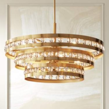 Modern three-tier gold crystal chandelier hanging as a luxury ceiling light fixture in a dining room.