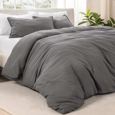 Modern charcoal grey duvet cover set on a white bed with matching pillow shams in a bright bedroom.