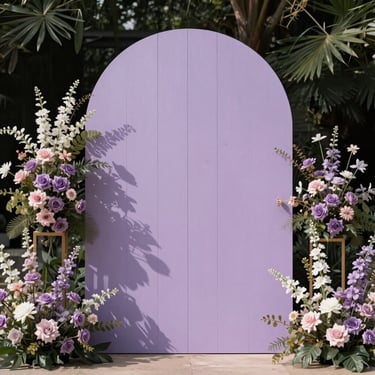 A minimalist, arch-shaped wooden backdrop painted in soft lilac, flanked by structural floral installations in natural light.