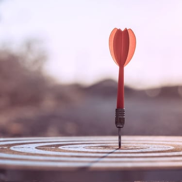 A single red dart hitting the bullseye on a target, representing business success and goals.