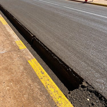 A deep pothole being filled and compacted with specialized road repair materials, showing clean edges and dense compaction