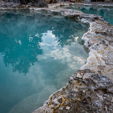 A detail shot of thermal waters in a natural stone pool, reflecting a turquoise sky, representing healing and physical restoration in Tequisquiapan.