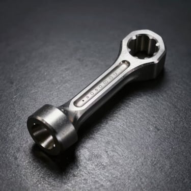 Heavy-duty steel connecting rod, shot from above on dark metallic surface, dramatic lighting