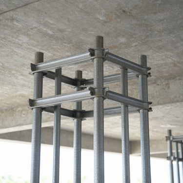 Sharp commercial photo of steel shoring props supporting a concrete ceiling structure, bright daylight, realistic 35mm lens