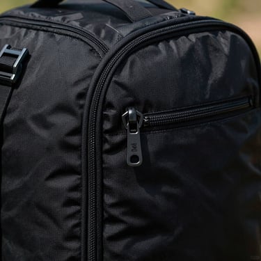 Close-up of a durable black ballistic nylon travel backpack zipper and water-resistant seam.