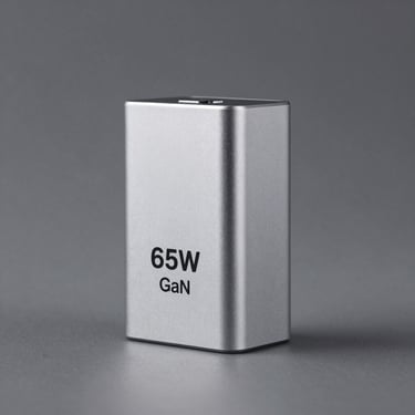 Centered studio shot of a compact 65W GaN charger in anodized aluminum, clean gray background