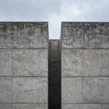 Symmetrical architectural shot of a modern industrial concrete facade under a cool overcast sky.