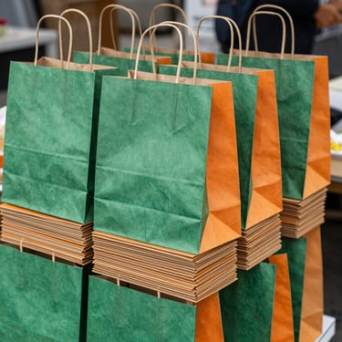 Stack of eco-friendly paper bags with handles, ready for packaging products at a market stall, natural daylight.