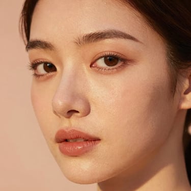 Warm editorial portrait of a woman with radiant skin, soft golden hour glow, natural makeup look.
