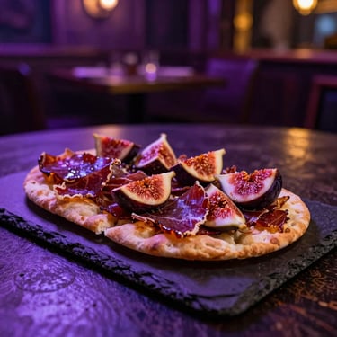 Gourmet flatbread with dark cured meats and figs on a slate platter, moody low-key tavern lighting.