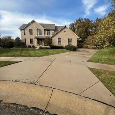 Modern two-story brick luxury home with a large concrete driveway and manicured green lawn.