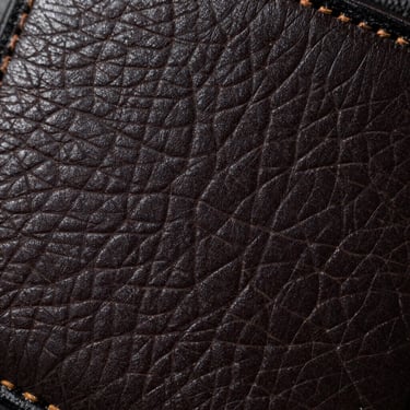 Extreme close-up of a debossed genuine leather patch, showing deep stamped lines and natural grain texture, hard side-lighting