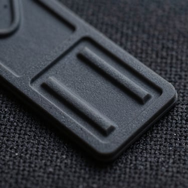 Macro shot of a molded PVC rubber patch, showing waterproof raised 3D details and sharp molded edges, textured canvas background