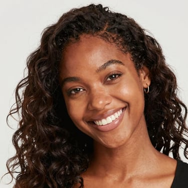 A joyful portrait of a person laughing outdoors with soft natural light.