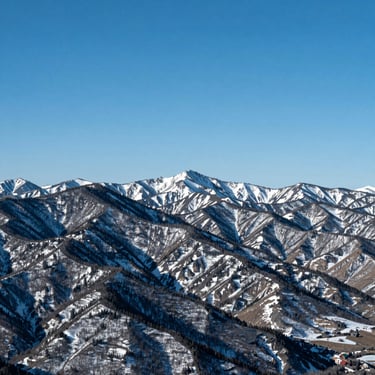 Wide scenic view of snow-capped Park City mountains under crisp blue sky, sharp daylight, minimalist aesthetic