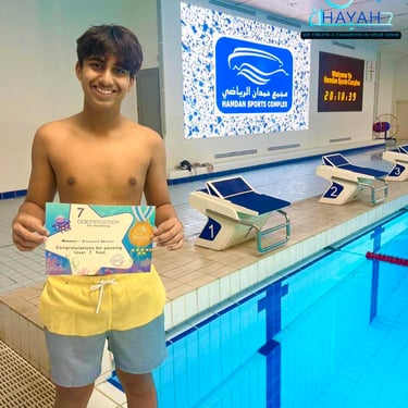 A young swimmer holds his level 7 swimming certificate at the Hamdan Sports Complex pool.